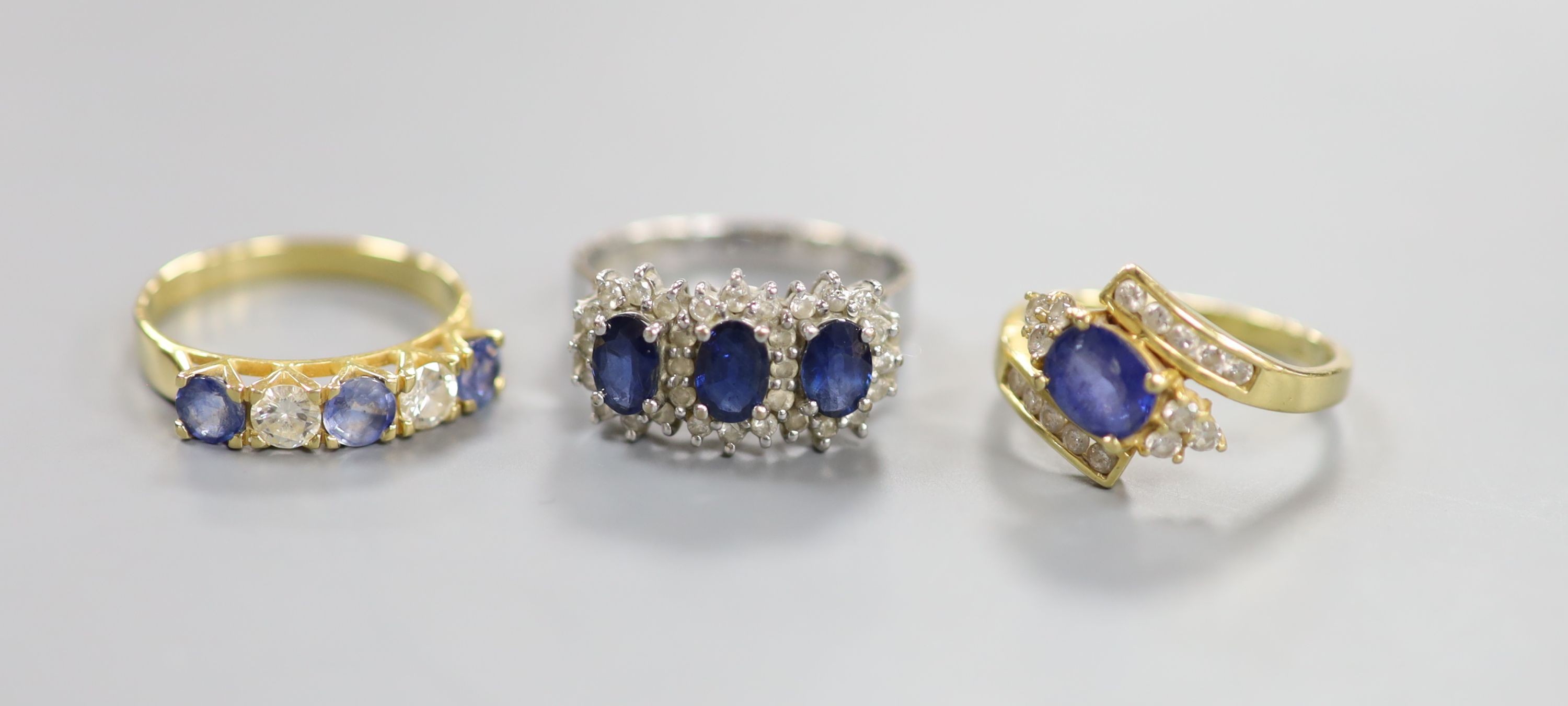 A modern 7560 white metal, sapphire and diamond set triple cluster ring, size Q/R and two other 18k, sapphire and diamond set dress rings, including half hoop, sizes O & N, gross weight 13.1 grams.